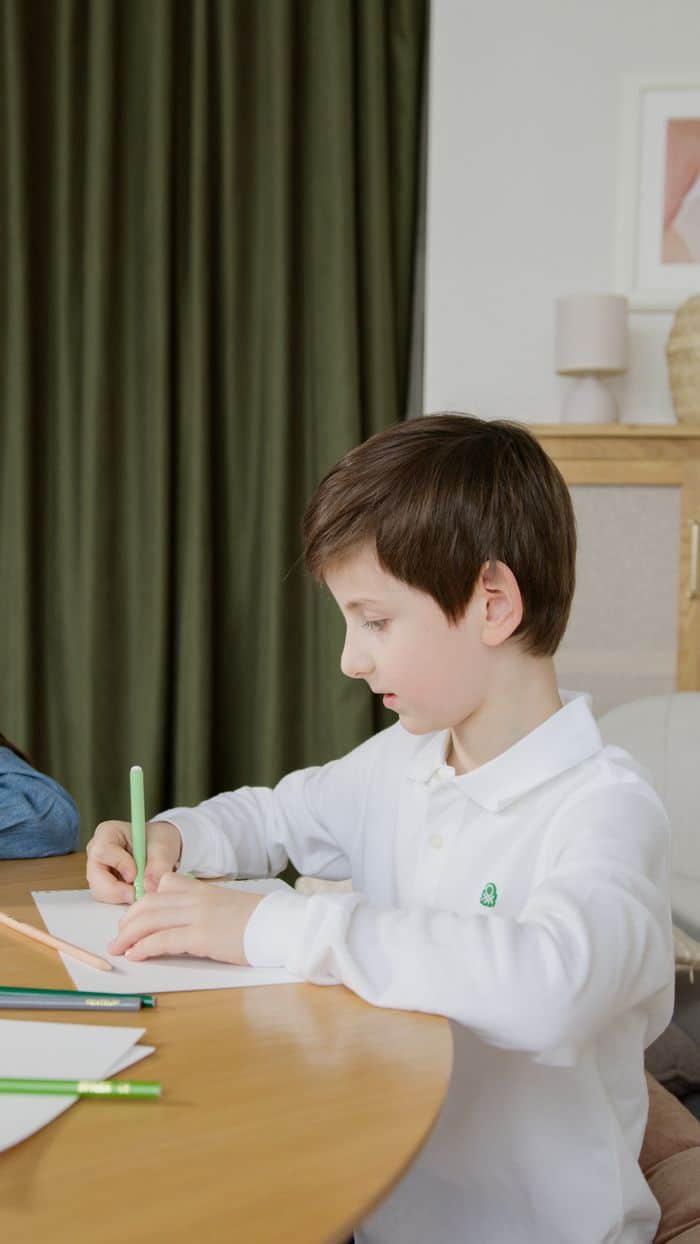 Child focused on writing at a desk in an educational environment.